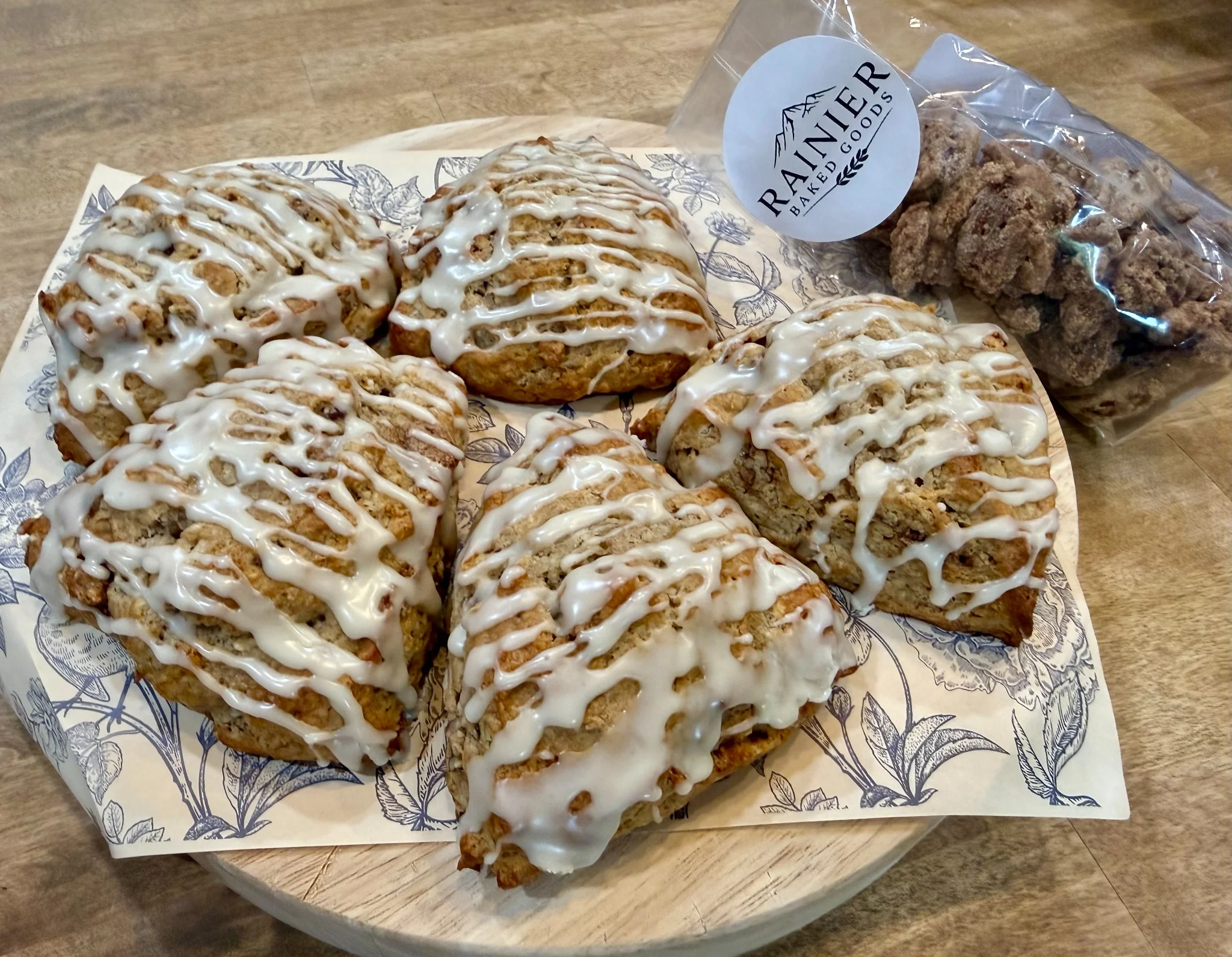 Glazed cinnamon rolls, oat scones and blondies arranged on a slate board with rosemary